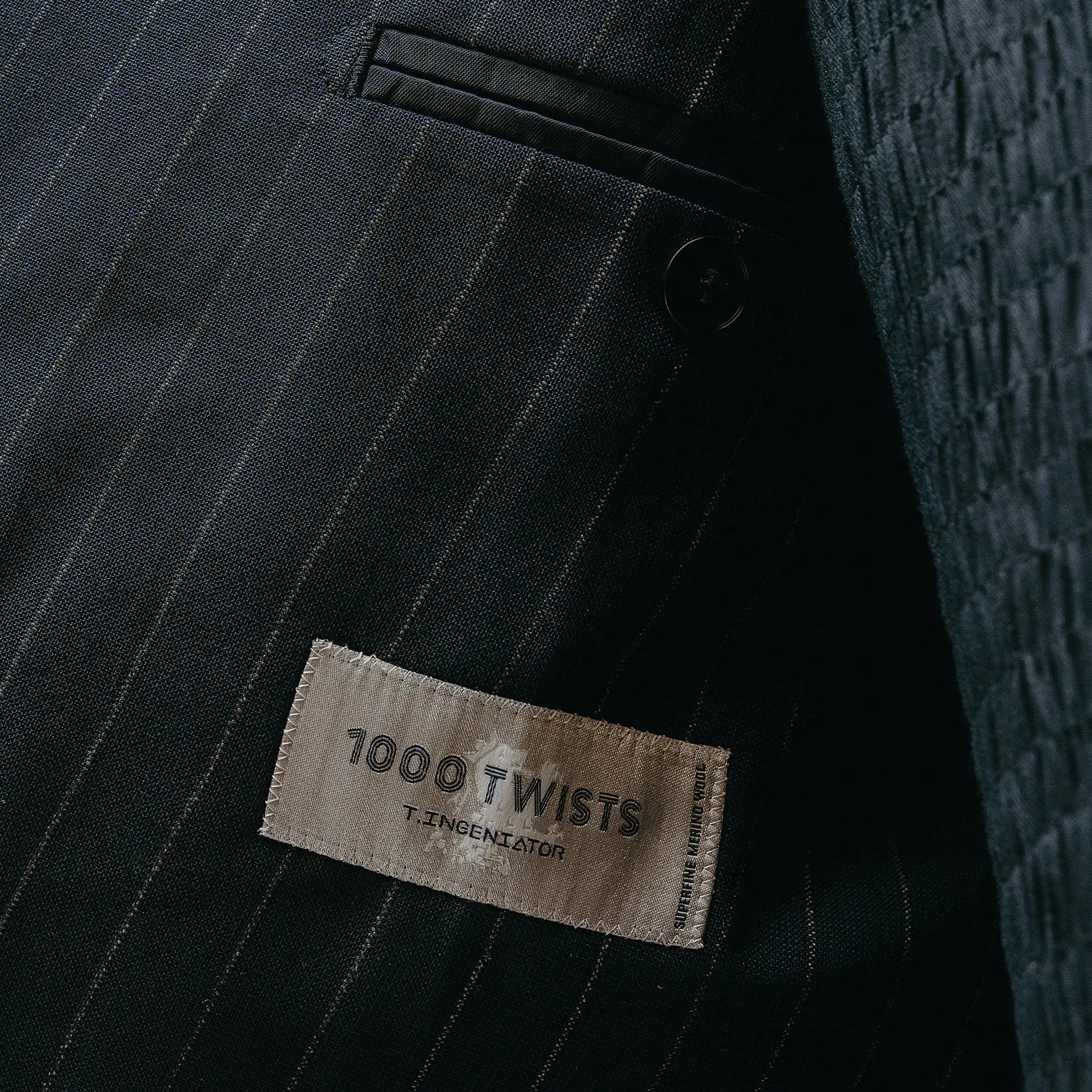Fabric label detail of the Drop6 Wool Chalk Stripe Double Breasted Suit Navy showing the cloth tag, chalk stripe wool fabric, and material identification for Clothier & Sons.