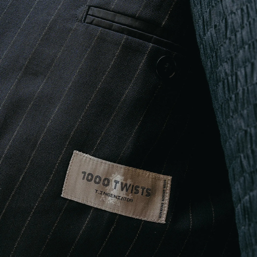 Fabric label detail of the Drop6 Wool Chalk Stripe Double Breasted Suit Navy showing the cloth tag, chalk stripe wool fabric, and material identification for Clothier & Sons.