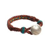 Front view of the Chamula Concho Bracelet #22 Bur/Gld x Grn showing the woven leather strap in burgundy and gold tones with green accent and a concho centerpiece for Clothier & Sons.