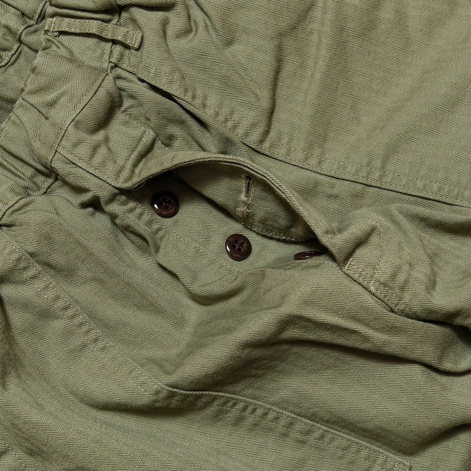 Fabric detail of the Omnigod Men’s Herringbone Easy Baker Pants Olive revealing herringbone weave texture, durable cotton fabric, and earthy olive coloration for Clothier & Sons.