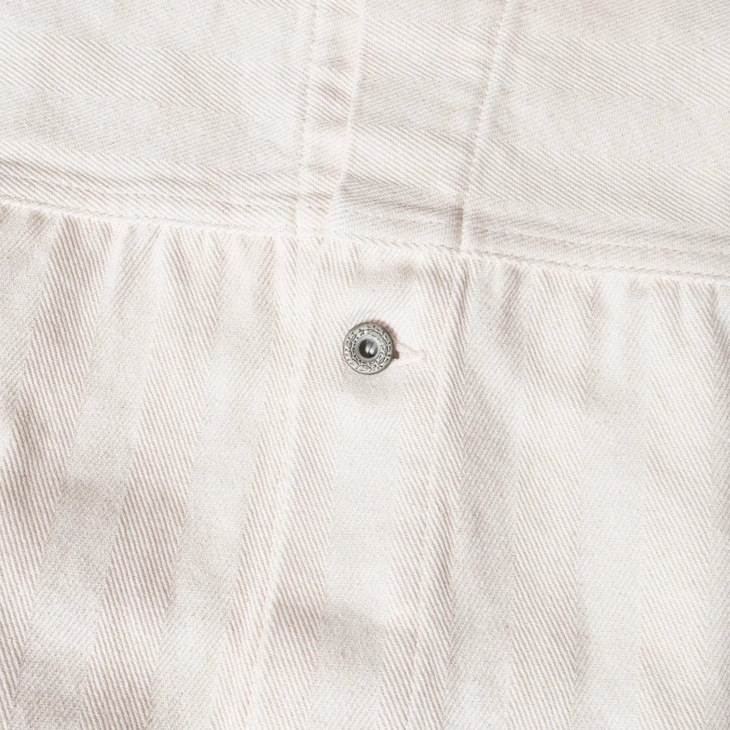 Close-up of metal button fastening on Seuvas Herringbone Trucker Jacket in natural.