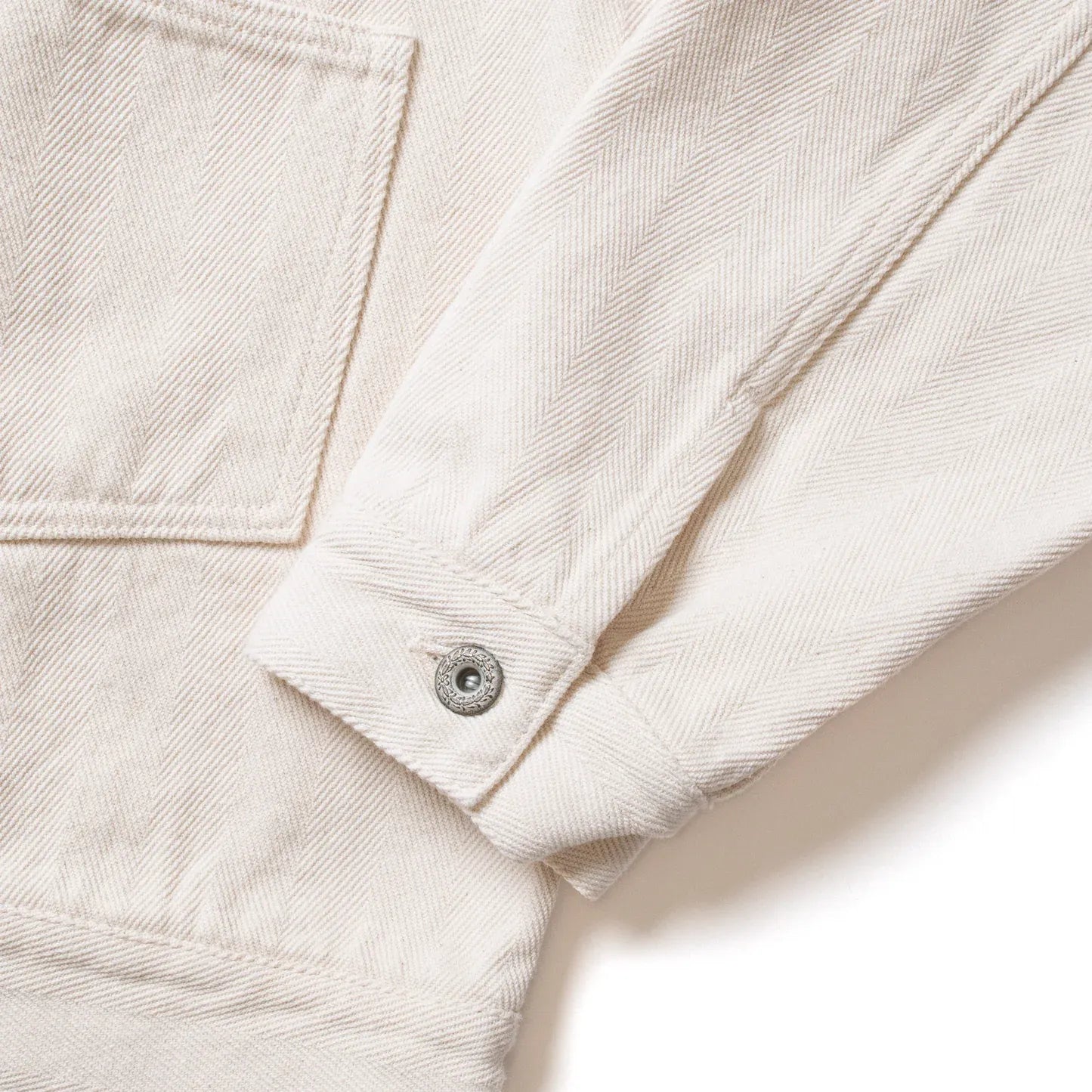 Close-up of sleeve seam and cuff construction on Seuvas Herringbone Trucker Jacket in natural.
