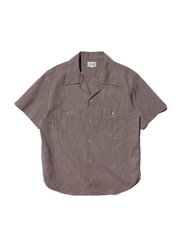 A close-up view of the JELADO Mechanic Shirt in a white cypress color, showcasing the textured cotton chambray fabric, open-collar design, and subtle puckering around the shoulder, reflecting a vintage 1930s-1940s work shirt style.